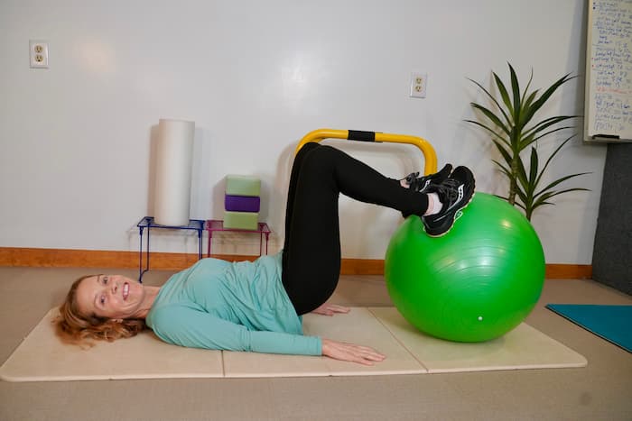 in home personal trainer demonstrates workout on ball